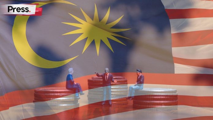 Miniature figures discussing Malaysia’s 2026 Budget with stacked coins and national flag background.