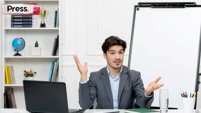 A man sits at the front of a classroom teaching. Behind him is a shelf full of teaching instruments like globes and books, and there is a blank whiteboard next to that shelf, where he may be preparing to write about AI SEO.
