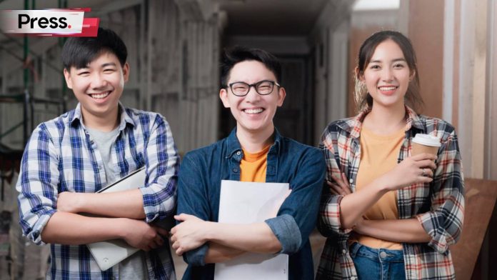 Three students (two male one female) standing in front of their university building, dressed in casual clothes. They are all happy and smiling as they hold their files, clearly because they made the right decisions and picked the right universities in Malaysia.