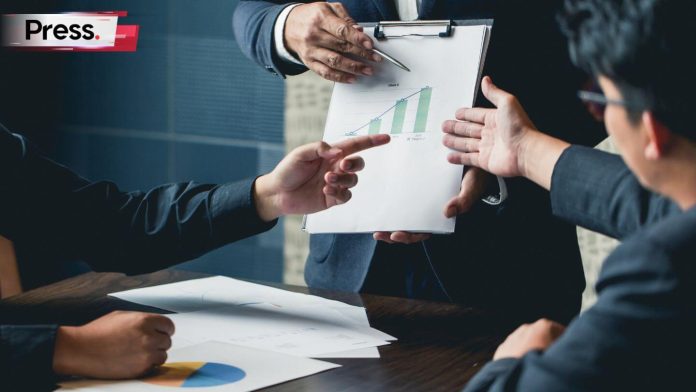 Business professionals discussing company valuation, with one person holding a clipboard showing a rising bar chart during a financial meeting.