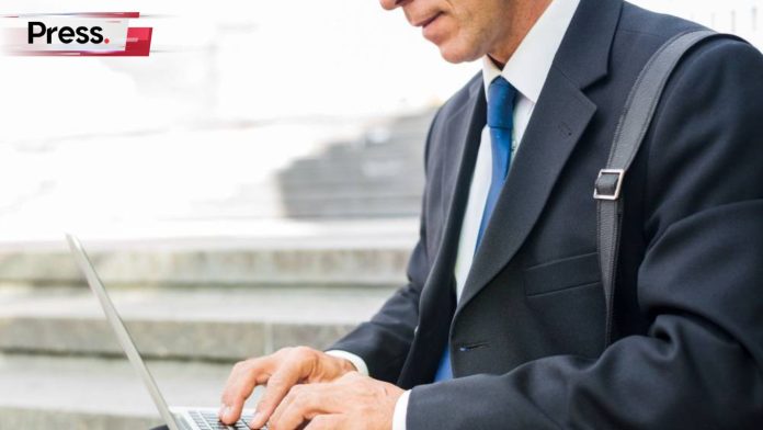 A faceless businessman in formal attire sits typing on his laptop, adjusting the SEO landing pages of his websites.