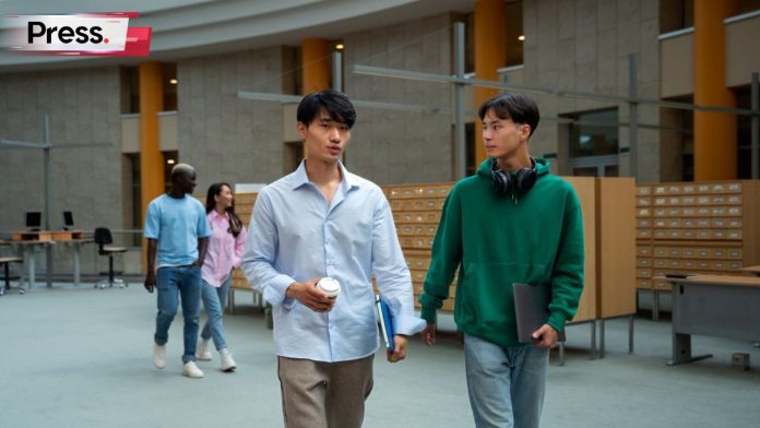 Two men, university students, walking on campus and discussing tertiary education meaning.