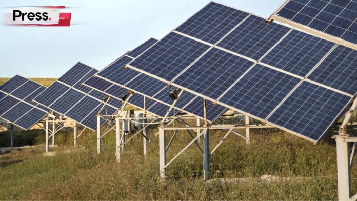 A photo of a row of blue-colored solar panels in a field, standing under the afternoon sun.
