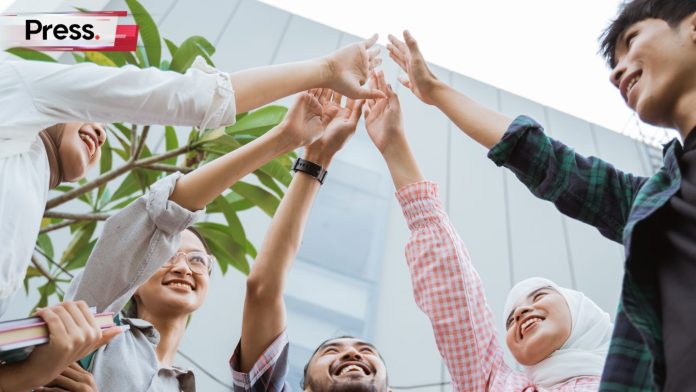 A group of employees hands up together smiling