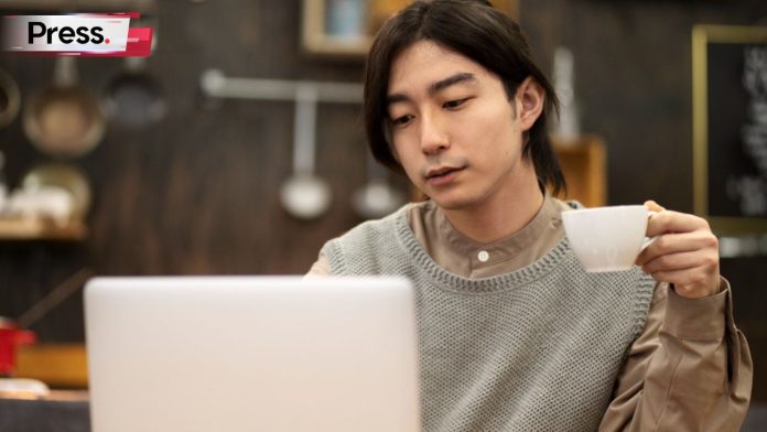 A worker is looking at his laptop, with a coffee cup in hand. He is learning how SGE works.
