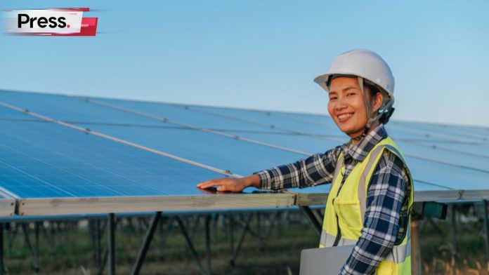 Female construction worker stands next to a solar panel with her hand on it. This represents the implementation of Solar ATAP in Malaysia.