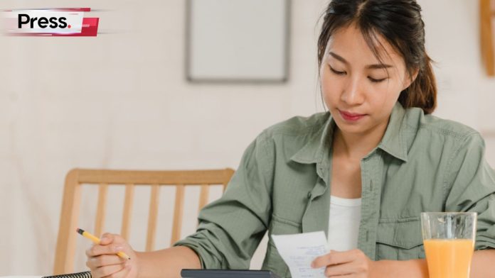 A woman sits at her desk calculating her good debt vs bad debt