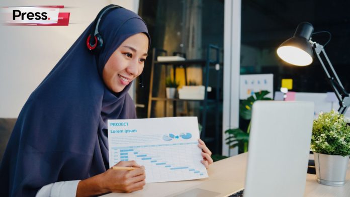 A Muslim lady shows her report on SEO content to her colleagues over a video call.