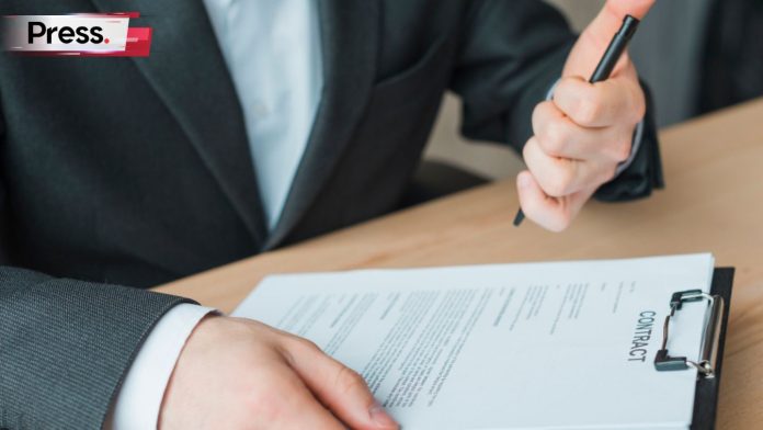 A businessman is writing on a paper, filling in their employee's probation evaluation