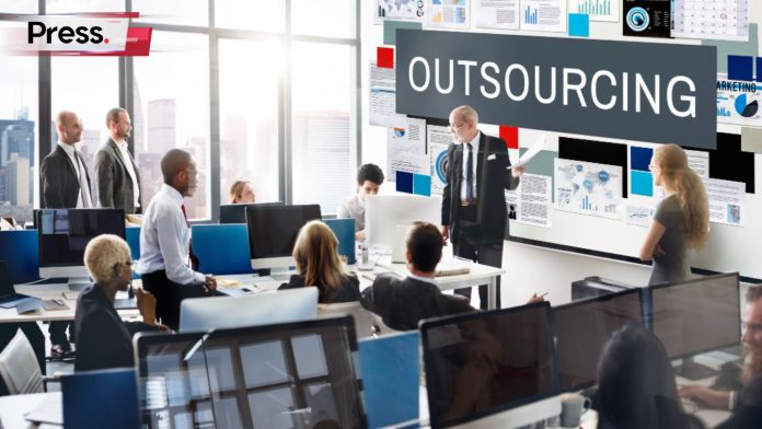 A group of businesspeople in a room, discussing whether to outsource services.