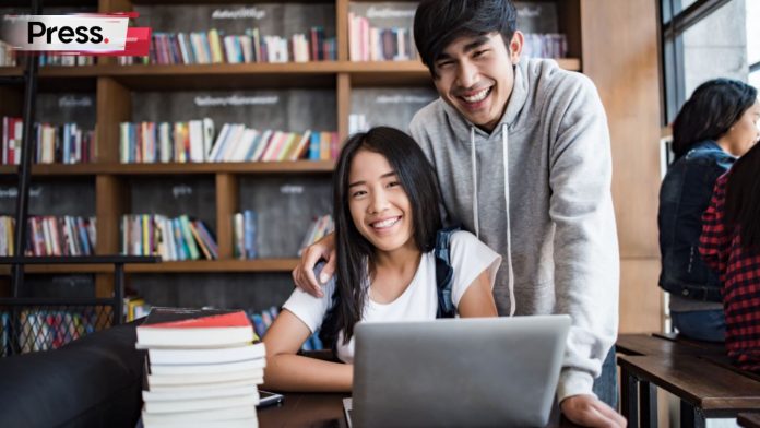Two university students, a man and woman, smile at the camera as they study for an MQA course.